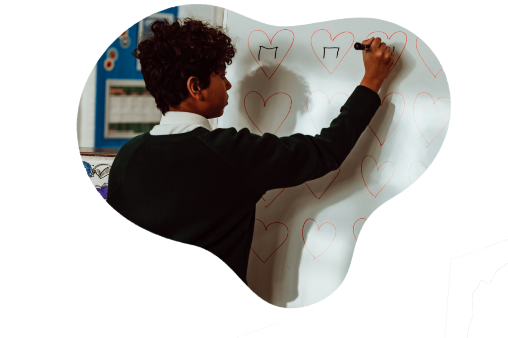 A student in a school uniform is focused on writing musical notes inside heart shapes on a whiteboard, suggesting a creative and engaging approach to learning music theory. The classroom setting and the student's concentration convey a sense of discovery and enjoyment in the educational process.