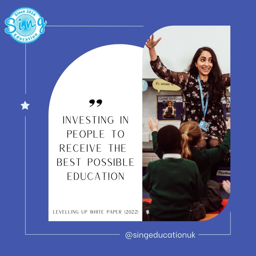 A joyful educator with outstretched arms is engaging with young students in a classroom setting, embodying the quote "Investing in people to receive the best possible education" from the Levelling Up White Paper (2022). The image conveys a sense of enthusiasm and commitment to educational excellence, as reflected by Sing Education's mission.