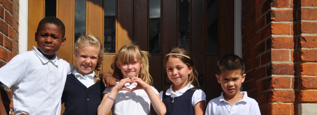Victoria road students are standing outside the front door. One student is making a heart shape with her hands