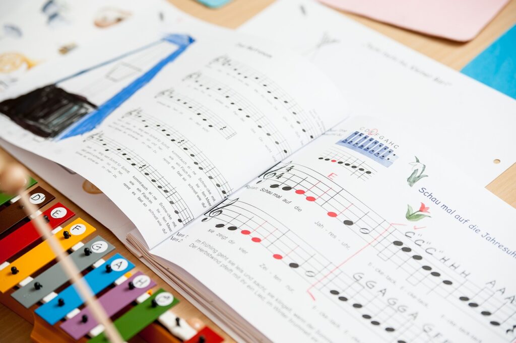 A book to help children learn how to read and play music is lying open on the table. A colourful glockenspiel is in the bottom left corner