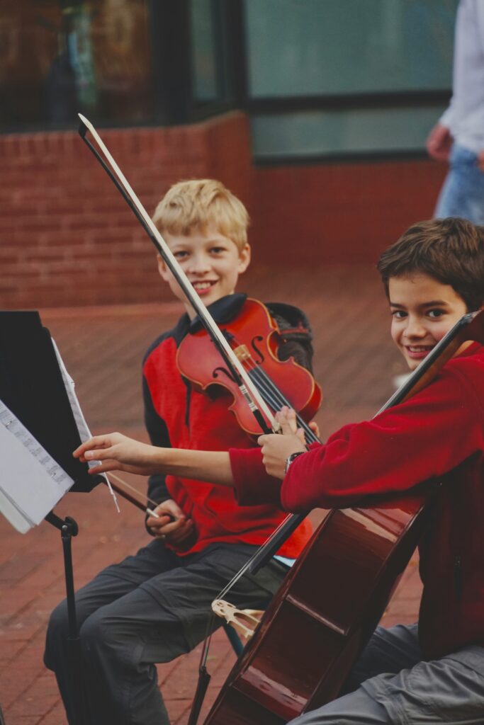 Two school children are playing string instruments in the playground