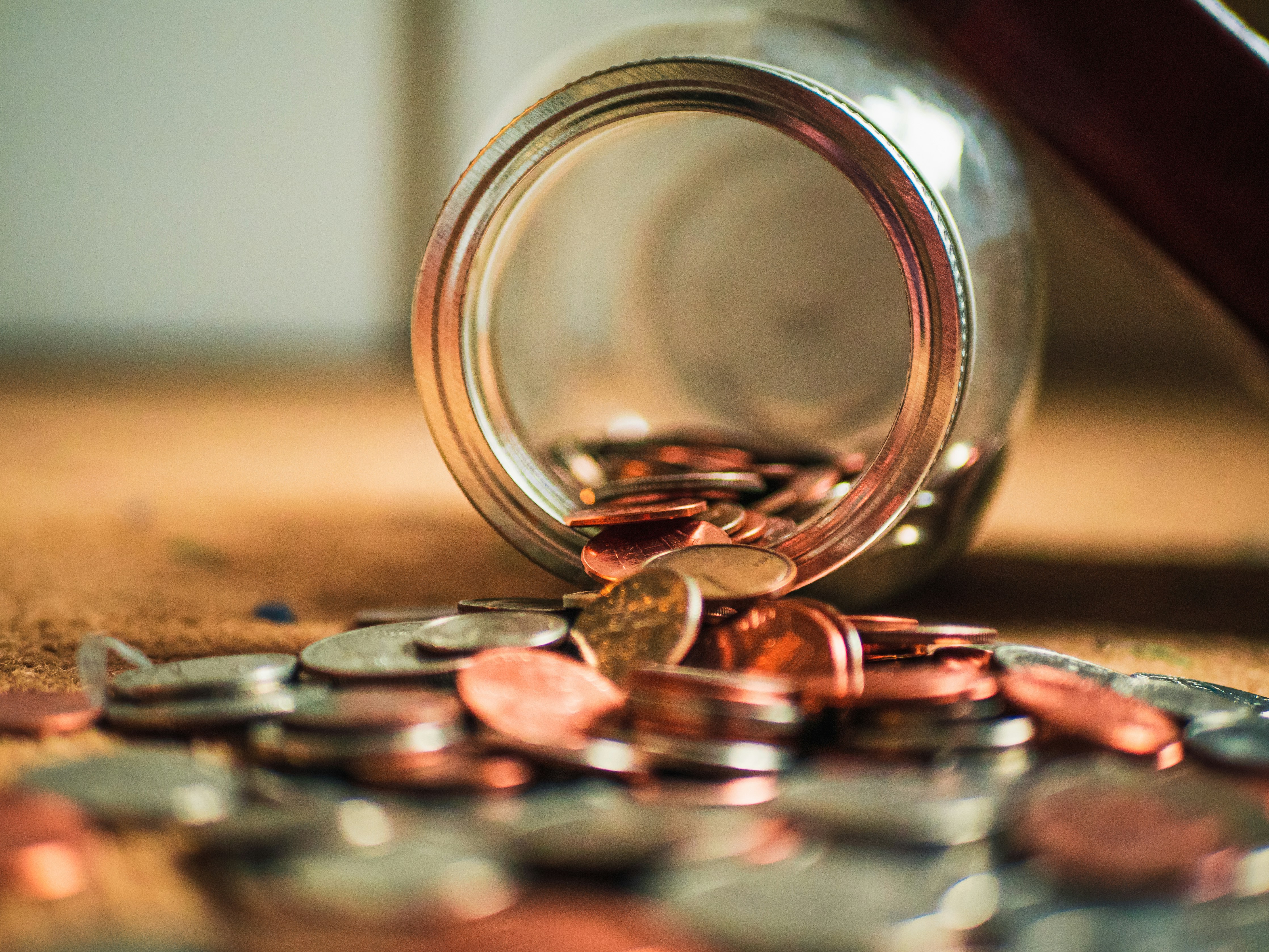 A jar of coins is spilling over the table